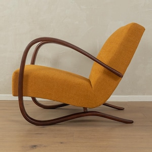 May include: An orange mid-century modern armchair with a curved wooden frame. The chair has a high back and a low seat, with a curved wooden armrest. The chair is upholstered in a textured orange fabric.