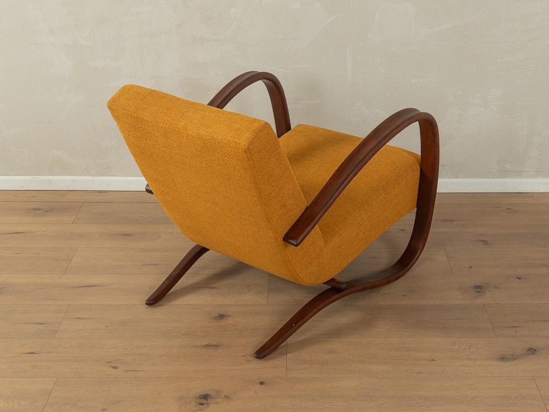 May include: An orange upholstered armchair with dark brown wooden frame and curved armrests. The chair has a low profile and a mid-century modern design, with a slightly reclined backrest and angled legs.