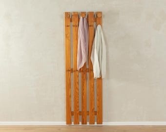 May include: A wooden coat rack with five hooks and two scarves hanging on it. The coat rack is made of natural wood and has a rustic look.
