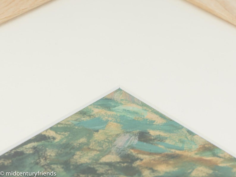 Puede incluir: Primer plano de una esquina de una obra de arte enmarcada. La obra presenta pinceladas abstractas en tonos verdes, azules y dorados.