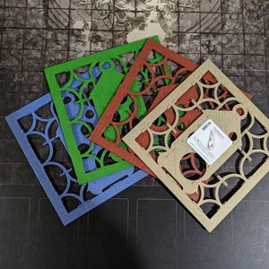 May include: Four decorative, laser-cut, wooden tiles with intricate patterns. The tiles are in shades of blue, green, brown, and beige. The beige tile has a small card attached to it with the text "Founding Stone".