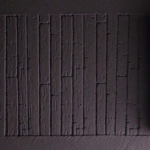 May include: A dark gray textured silicone mold with a wood plank design. The mold is rolled up and ready to be used for baking.