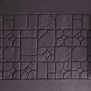 Op de afbeelding: Een donkergrijze, textuurrubberen stempel met een patroon van onregelmatige stenen blokken. De stempel is opgerold en klaar voor gebruik.