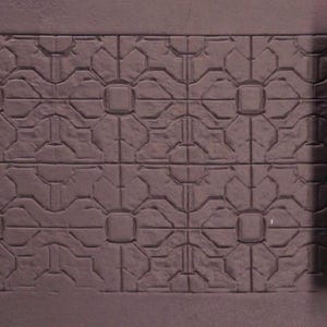 May include: A brown textured roller with a repeating pattern of four-leaf clover designs. The roller is partially rolled out on a brown surface, revealing the pattern it creates.