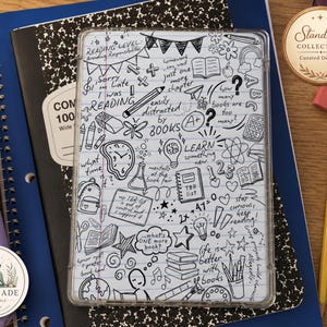 May include: A rectangular e-reader case featuring a white lined paper background covered in black hand-drawn doodles, including books, lightbulbs, a clock, a pencil, and various phrases like Reading Level: Avoiding Responsibilities and TBR list.