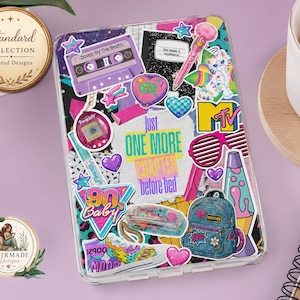 Puede incluir: Una funda transparente para tableta cubierta con pegatinas de los años 90, que incluye un casete morado con la etiqueta Saved By The Beats, un estuche rosa en forma de corazón, una lámpara de lava, una mochila de mezclilla y el texto just ONE MORE CHAPTER before bed.