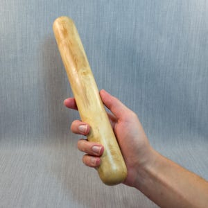 以下が含まれることがあります： 滑らかな明るい茶色の仕上げと、自然な木目が目に見える円筒形の木製麺棒。この物体は丸みを帯びた端と磨かれた表面が特徴で、有機的な質感と明るい木材の色の変化を際立たせています。