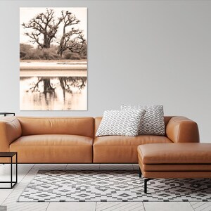 May include: A sepia toned photograph of a large tree with its reflection in a body of water. The tree is bare and has many branches. The water is calm and reflects the tree perfectly.