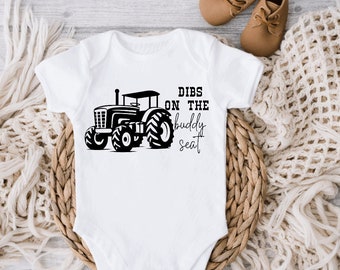 May include: White baby onesie with a black tractor graphic and the text "Dibs on the buddy seat".