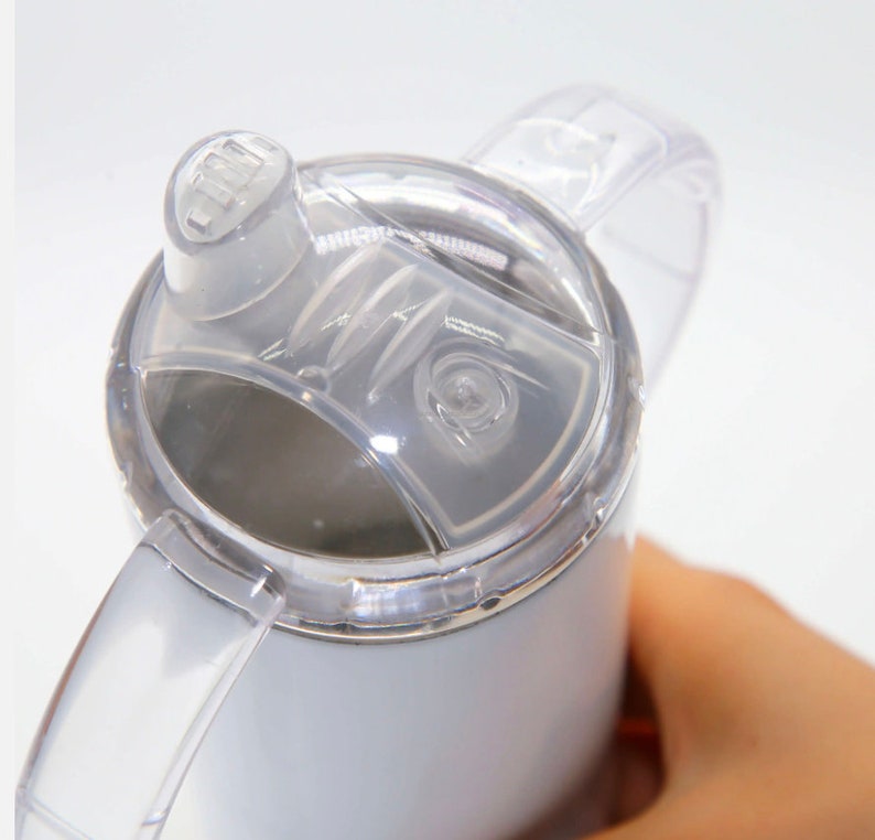 K&ouml;nnte beinhalten: Wei&szlig;e Reise-Thermoskanne aus Edelstahl mit einem durchsichtigen Deckel und einem durchsichtigen Griff. Der Deckel hat einen Klappverschluss zum Trinken.