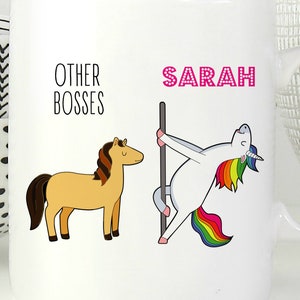 Puede incluir: Una taza de cer&aacute;mica blanca con un gr&aacute;fico de un caballo marr&oacute;n etiquetado como OTHER BOSSES y un unicornio blanco con crin y cola de arco&iacute;ris en un poste etiquetado como SARAH en texto rosa. La taza tiene un asa en el lado derecho.