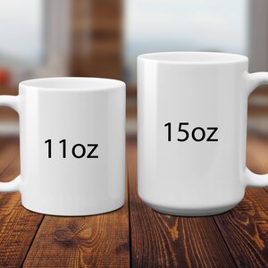 May include: Two white ceramic mugs with handles, one smaller mug labeled 11oz and one larger mug labeled 15oz. The mugs are plain, cylindrical, and feature a smooth, glossy finish. The text 11oz and 15oz is printed in black on the front of each mug.