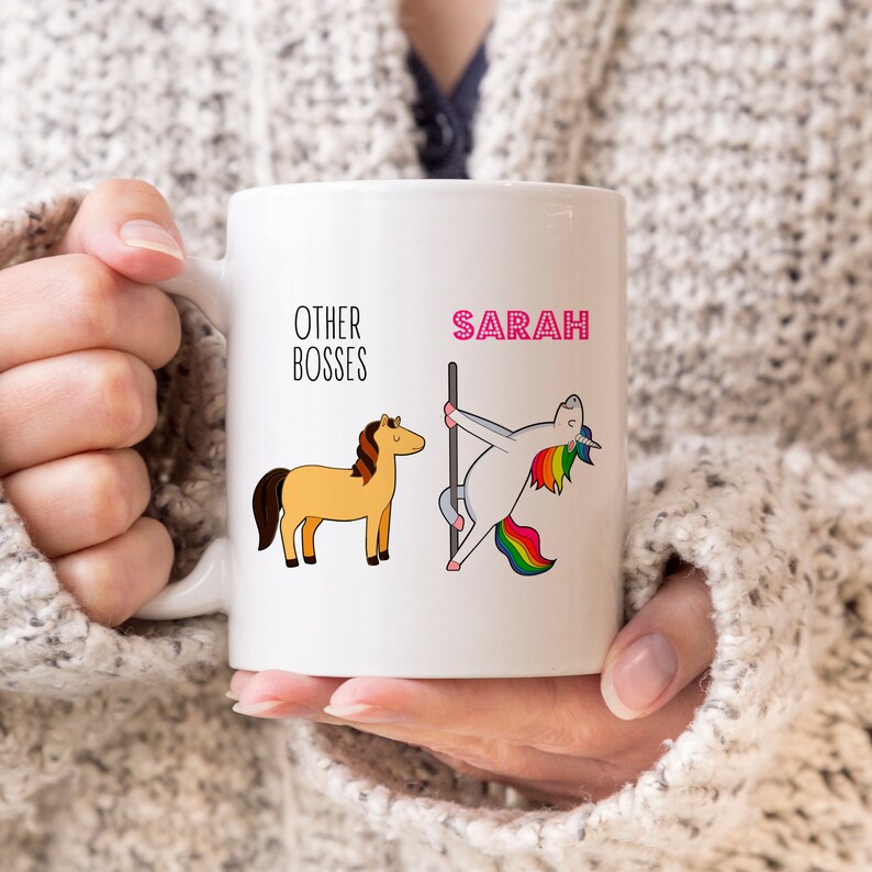 Puede incluir: Una taza de cer&aacute;mica blanca con una ilustraci&oacute;n gr&aacute;fica. A la izquierda, un caballo marr&oacute;n con el texto OTHER BOSSES. A la derecha, un unicornio blanco con crin y cola arco&iacute;ris bailando en una barra, con el nombre SARAH en rosa arriba.