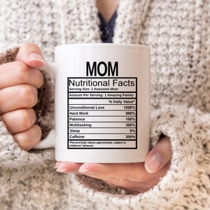 May include: A white ceramic mug featuring black text that reads MOM Nutritional Facts, listing ingredients like Unconditional Love at 1000%, Hard Work at 500%, Patience at 100%, Multitasking at 300%, Sleep at 0%, and Caffeine at 300% with a disclaimer.