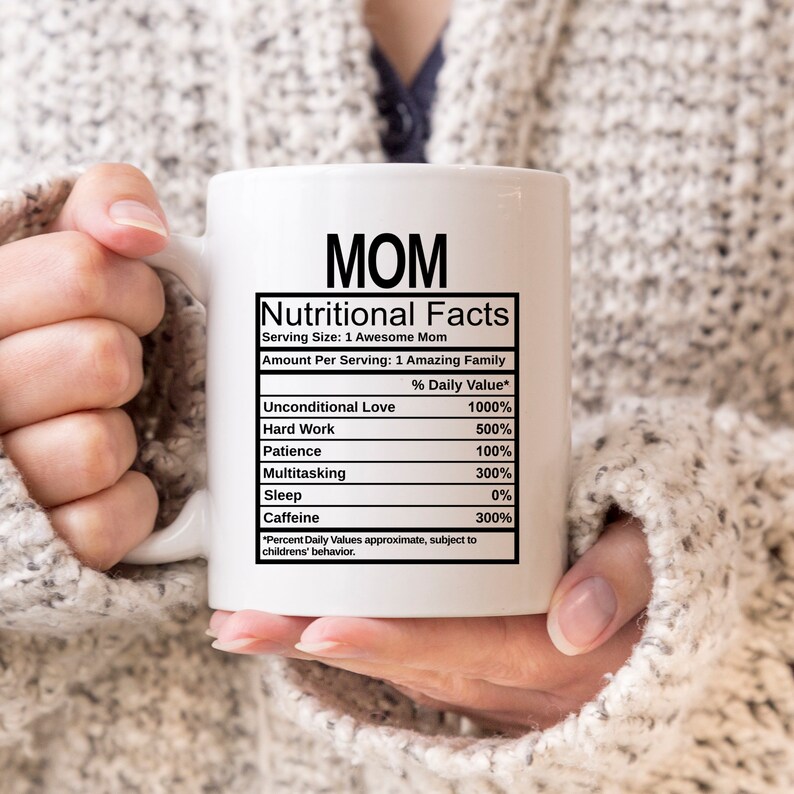 May include: A white ceramic mug featuring black text that reads MOM Nutritional Facts, listing ingredients like Unconditional Love at 1000%, Hard Work at 500%, Patience at 100%, Multitasking at 300%, Sleep at 0%, and Caffeine at 300% with a disclaimer.