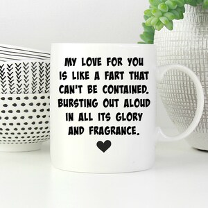 May include: A white ceramic mug featuring black text that reads: MY LOVE FOR YOU IS LIKE A FART THAT CAN'T BE CONTAINED. BURSTING OUT ALOUD IN ALL ITS GLORY AND FRAGRANCE. A small black heart icon is printed below the text on the front of the mug.