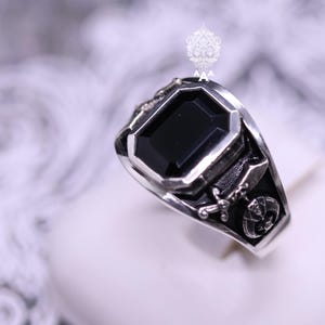 May include: A silver ring with a black gemstone and Masonic symbols.