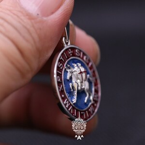 May include: Silver pendant with a blue and red enamel design. The pendant features a knight riding a horse with the text "XPISTI + SIGE" around the edge.