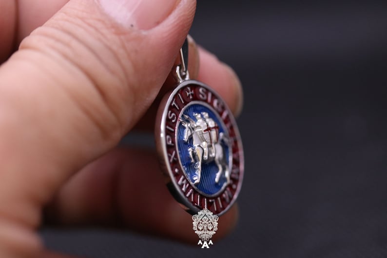 May include: Silver pendant with a blue and red enamel design. The pendant features a knight riding a horse with the text "XPISTI + SIGE" around the edge.