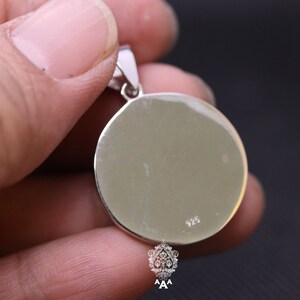 May include: Silver pendant with a round, smooth surface. The back of the pendant has the number 925 stamped on it.