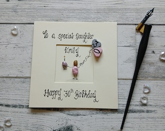 May include: A square greeting card with cream cardstock featuring the text To a special Daughter, Emily, and Happy 30th Birthday. The design includes a pebble art figure holding a cupcake and two heart-shaped balloons labeled 30.