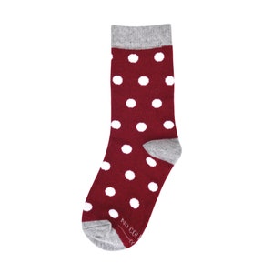 May include: A pair of red socks with white polka dots and a grey cuff. The socks have the text "NO COLL" on the bottom.