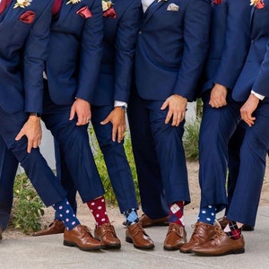 Wedding party posing for pictures on wedding day with their groomsman gifts of burgundy and navy groomsmen socks. Navy suits and brown shoes with navy and burgundy groomsmen socks.