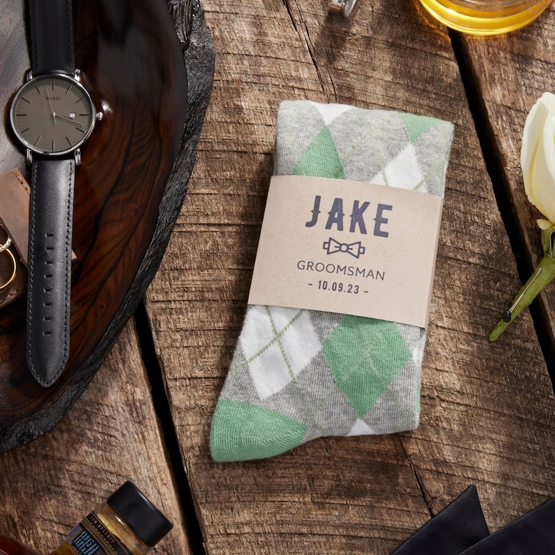 Sage green argyle socks with custom groomsmen label surrounded by groomsmen accessories on the wedding day.Sage Green Personalized Groomsmen Socks with Custom Labels, Sage Green Argyle Groomsmen Gift, Agave Wedding Socks for Groomsman and Groom