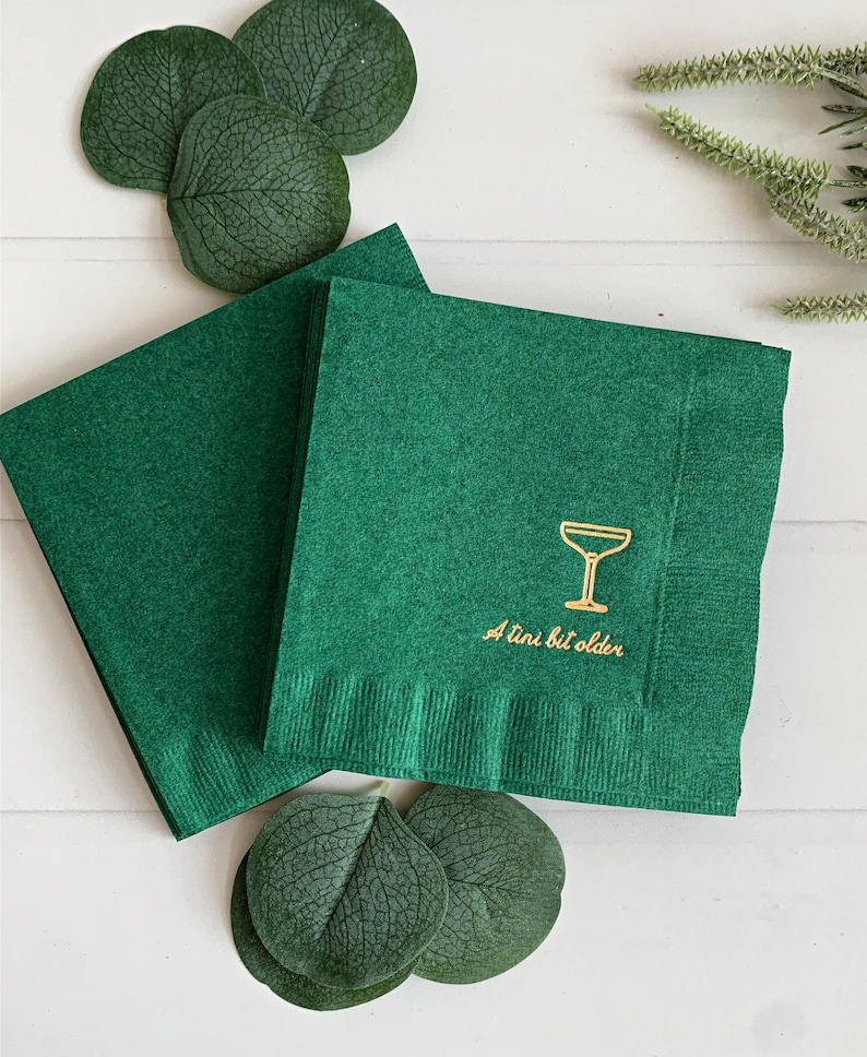 Celebrate a milestone in style with these charming A Tini Bit Older Martini Cocktail Napkins, the perfect addition to any martini-themed birthday party or sophisticated gathering. Designed for lovers of elegant cocktails, these foil-stamped napkins feature a chic illustration of a classic coup martini glass wrapped with a delicate bow around the stem, adding a playful yet refined touch to your celebration. These are perfect for any age birthday, give them as gift for the martini lover.