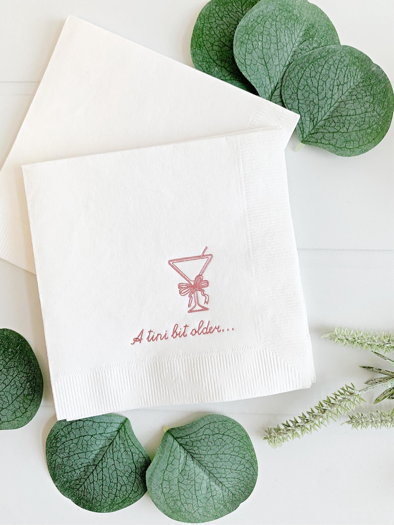 Celebrate a milestone in style with these charming A Tini Bit Older Martini Cocktail Napkins, the perfect addition to any martini-themed birthday party or sophisticated gathering. Designed for lovers of elegant cocktails, these foil-stamped napkins feature a chic illustration of a classic coup martini glass wrapped with a delicate bow around the stem, adding a playful yet refined touch to your celebration. These are perfect for any age birthday, give them as gift for the martini lover.