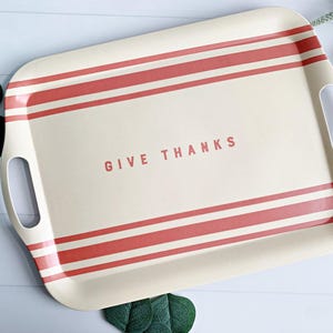 May include: A rectangular serving tray with red and white stripes and the words "Give Thanks" printed in the centre. The tray has two handles on the sides.