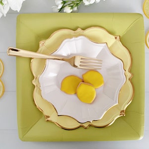 Puede incluir: Un juego de tres platos de papel amarillos y blancos con ribete dorado. Los platos est&aacute;n apilados uno encima del otro y tienen un borde festoneado. Hay tres galletas con forma de lim&oacute;n amarillas en el plato superior. Un tenedor dorado est&aacute; en el plato.