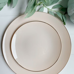Pu&ograve; includere: Due piatti in ceramica color crema con un bordo dorato. Il piatto pi&ugrave; piccolo &egrave; annidato all'interno del piatto pi&ugrave; grande.