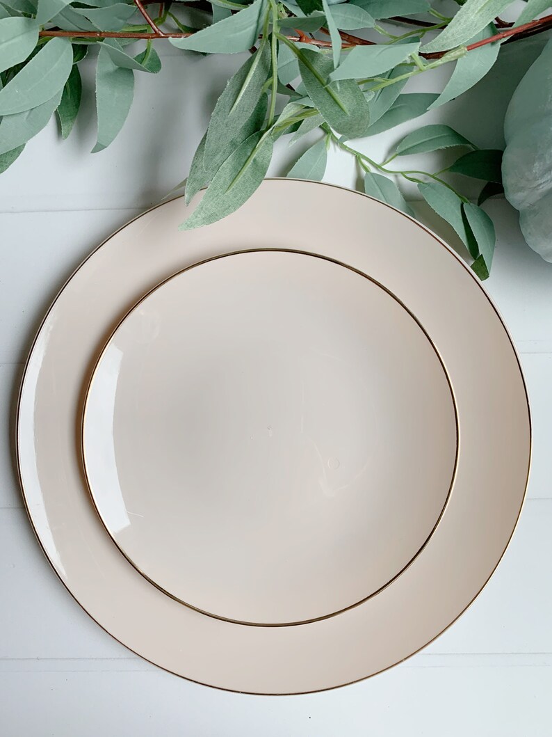Pu&ograve; includere: Due piatti in ceramica color crema con un bordo dorato. Il piatto pi&ugrave; piccolo &egrave; annidato all'interno del piatto pi&ugrave; grande.