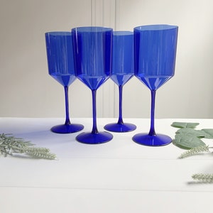 May include: Set of four cobalt blue glass wine glasses. The glasses have a tall, slender stem and a wide, round bowl.