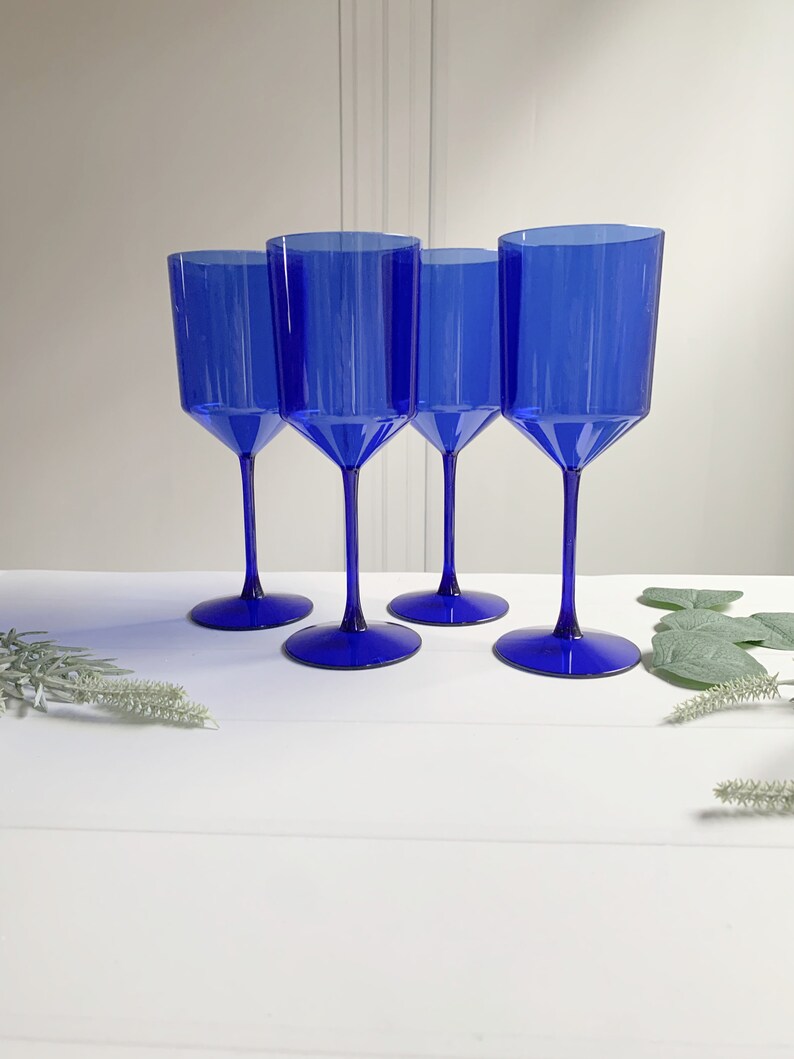 May include: Set of four cobalt blue glass wine glasses. The glasses have a tall, slender stem and a wide, round bowl.