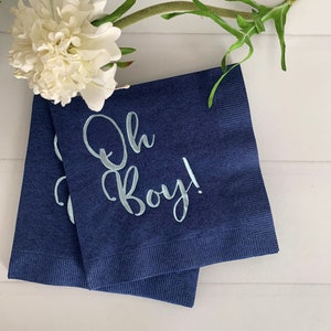 May include: Two navy blue paper napkins with white text that reads "Oh Boy!" in a light blue font.