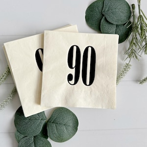 May include: Two white paper napkins with black text. The top napkin has the number "90" printed on it. The bottom napkin has a partial number visible.