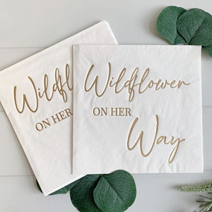 "Wildflower on her Way " in gold foil on white luncheon napkins - the perfect accent for your baby shower.  A fun baby shower theme for spring and summer babies. These gorgeous gold foiled "Wildflower on her Way " napkins are an EnFete original