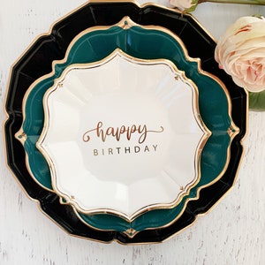 May include: A set of three paper plates in black, green, and white with a gold trim. The center plate has the words "happy birthday" written in gold script.