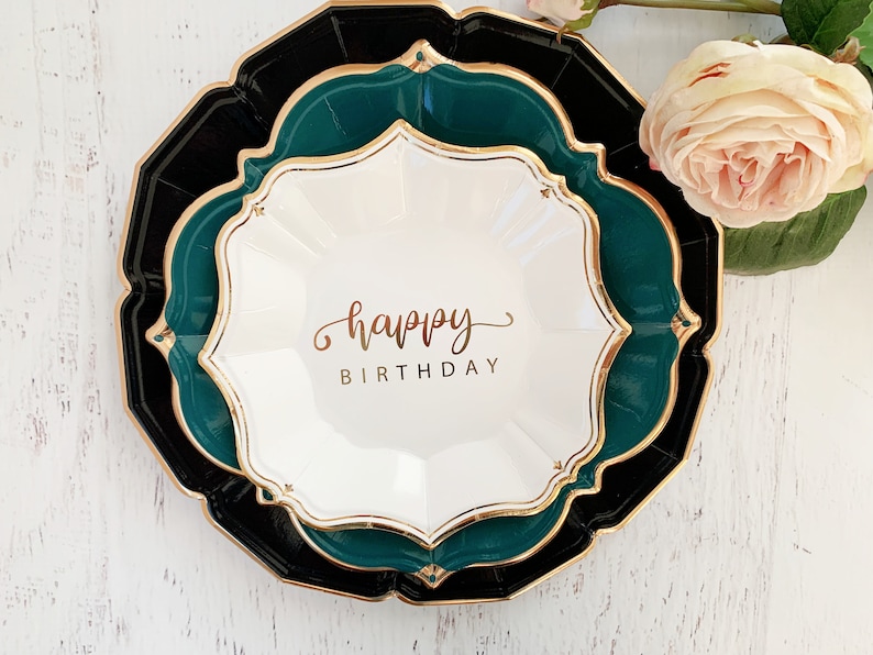 May include: A set of three paper plates in black, green, and white with a gold trim. The center plate has the words "happy birthday" written in gold script.