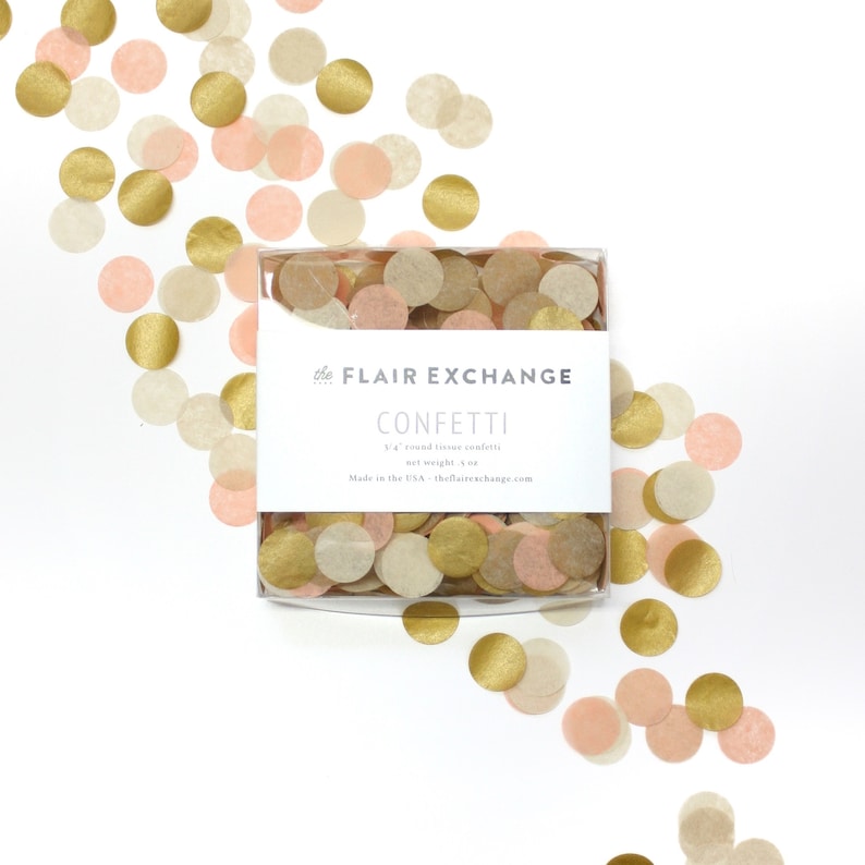 May include: A box of confetti with pink, gold, and cream tissue paper circles. The box has a white label with the text "The Flair Exchange Confetti 1/2 oz round tissue confetti net weight 1/2 oz Made in the USA - theflairexchange.com"