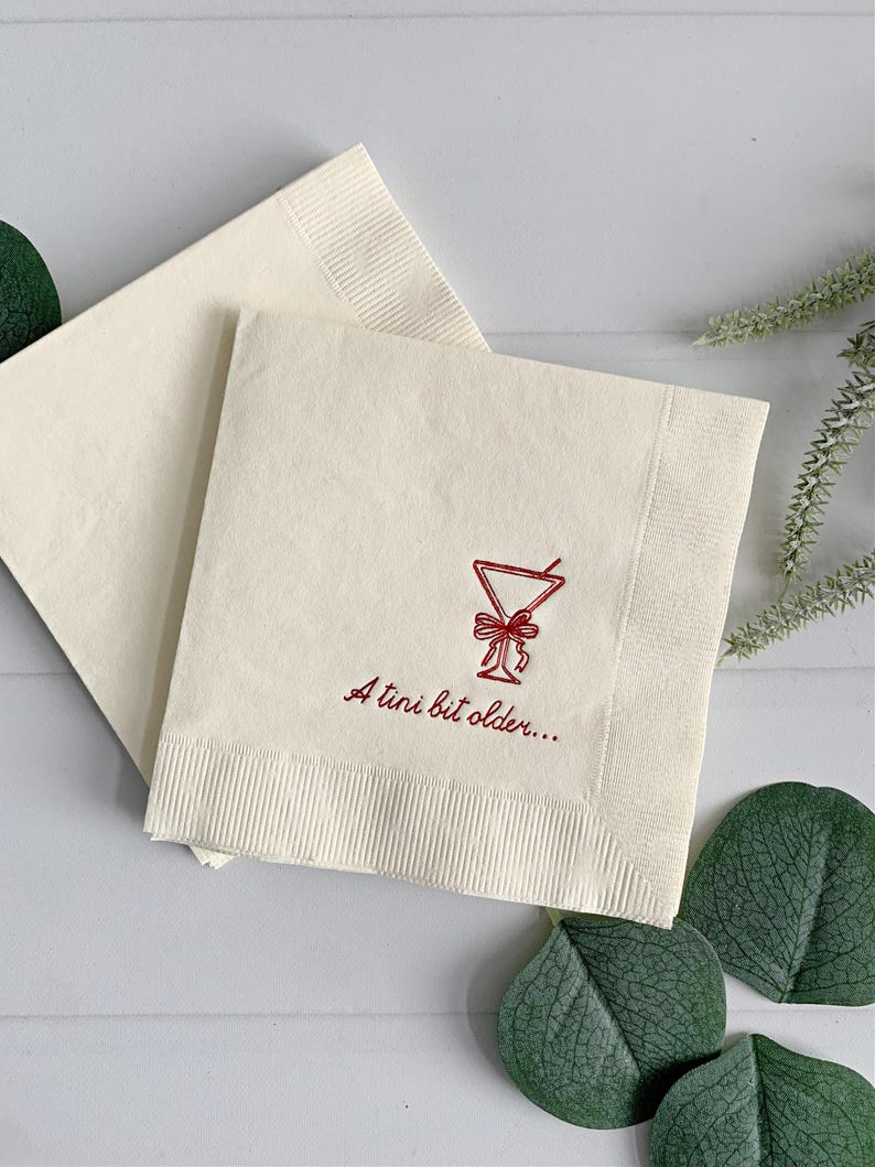 Celebrate a milestone in style with these charming A Tini Bit Older Martini Cocktail Napkins, the perfect addition to any martini-themed birthday party or sophisticated gathering. Designed for lovers of elegant cocktails, these foil-stamped napkins feature a chic illustration of a classic coup martini glass wrapped with a delicate bow around the stem, adding a playful yet refined touch to your celebration. These are perfect for any age birthday, give them as gift for the martini lover.