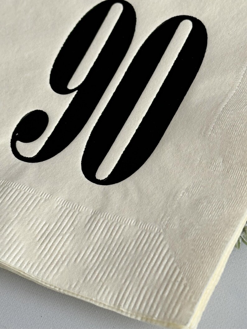 May include: A white paper napkin with the number "90" printed in black.
