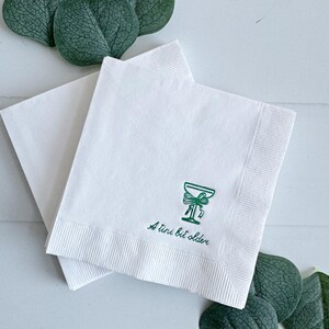 Celebrate a milestone in style with these charming A Tini Bit Older Martini Cocktail Napkins, the perfect addition to any martini-themed birthday party or sophisticated gathering. Designed for lovers of elegant cocktails, these foil-stamped napkins feature a chic illustration of a classic coup martini glass wrapped with a delicate bow around the stem, adding a playful yet refined touch to your celebration. These are perfect for any age birthday, give them as gift for the martini lover.