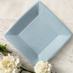 May include: A light blue square paper plate with a slightly textured surface.