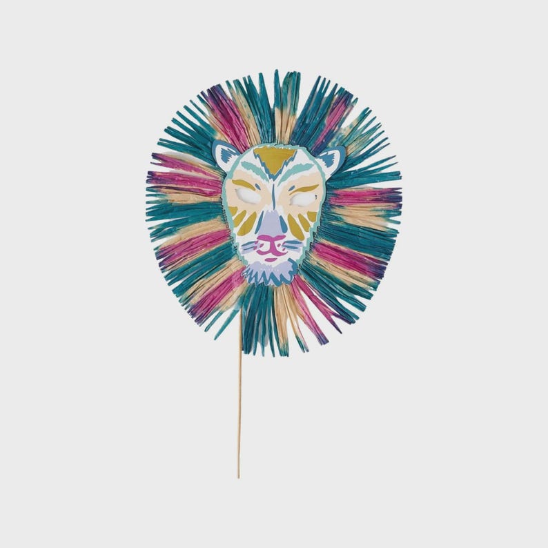 K&ouml;nnte beinhalten: Eine farbenfrohe L&ouml;wenmaske mit einer mehrfarbigen M&auml;hne in T&uuml;rkis-, Rosa- und Gelbt&ouml;nen. Das Gesicht des L&ouml;wen ist mit komplizierten Details bemalt, darunter geschlossene Augen und eine rosa Nase. Die Maske ist an einem Holzstab befestigt.