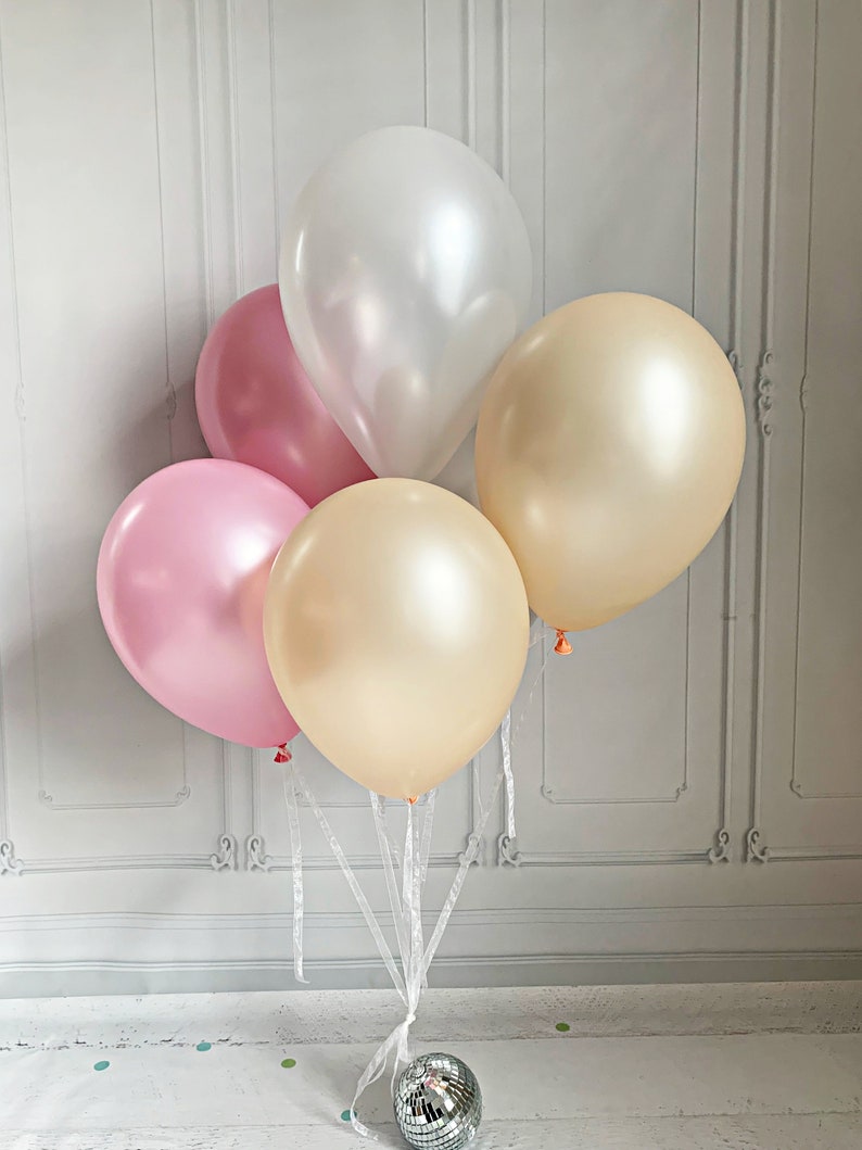 Puede incluir: Un grupo de cuatro globos en rosa, blanco y dorado atados con una cinta blanca. Los globos est&aacute;n dispuestos en forma de pir&aacute;mide con el globo blanco en la parte superior.