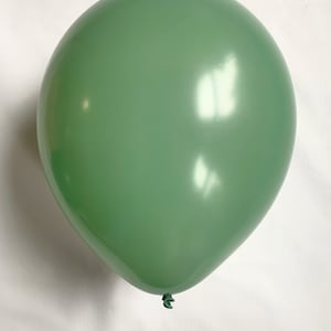 Puede incluir: Un solo globo verde salvia. El globo est&aacute; inflado y tiene una superficie lisa y brillante. El globo est&aacute; atado en la parte inferior con una cuerda verde. El fondo es una superficie blanca lisa.