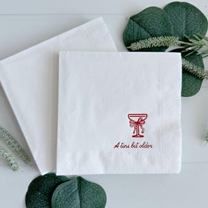 Celebrate a milestone in style with these charming A Tini Bit Older Martini Cocktail Napkins, the perfect addition to any martini-themed birthday party or sophisticated gathering. Designed for lovers of elegant cocktails, these foil-stamped napkins feature a chic illustration of a classic coup martini glass wrapped with a delicate bow around the stem, adding a playful yet refined touch to your celebration. These are perfect for any age birthday, give them as gift for the martini lover.